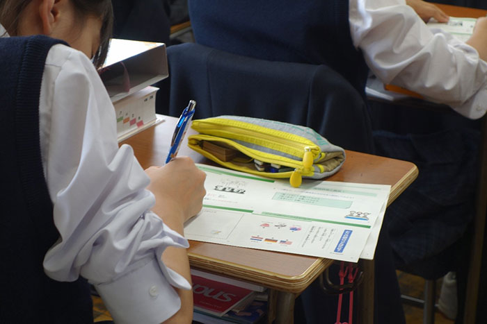 課題用プリントにことばの説明を書く女子生徒の後ろ姿