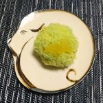 犬が丸まったベージュの和皿の上に、黄緑と黄色の餡の上に銀杏の葉をかたどった飾りの乗った和菓子の写真