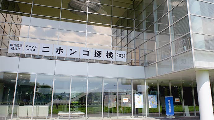 国立国語研究所の建物前景。国立国語研究所オープンハウスニホンゴ探検2024の看板が出ている