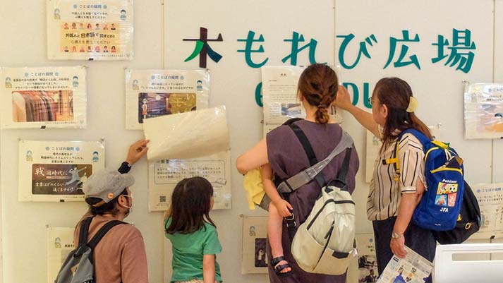会場の木もれ日広場にてことばの疑問めくりをめくって楽しむ親子連れ