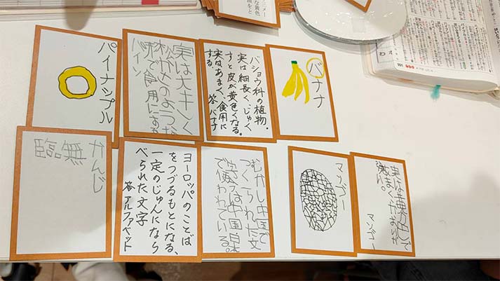 ワークショップできあがった国語辞典かるたの作品（バナナ、パイナップル、マンゴーなどの絵と対応する語釈カードが並んでいる）