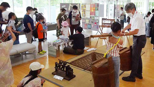 重そうな道具を持ち上げてみる少年の写真