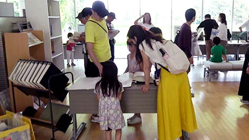 『日本言語地図』を開き、家族４人でのぞきこんでいる写真